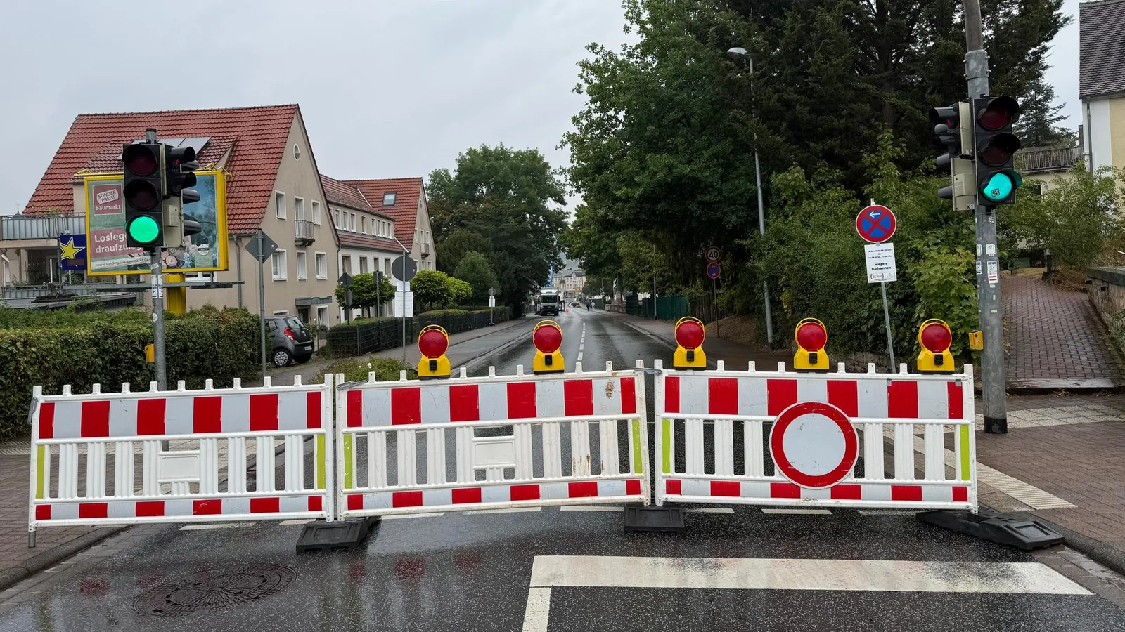Eine Straße in einer Kleinstadt ist mit rot-weißen Absperrungen blockiert.